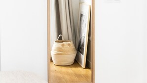 A mirror with a wooden frame, a beige curtain, and a woven basket on a wooden surface. - 7escalones Apartamentos Boutique (Rota)