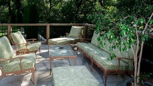 An outdoor patio with wicker furniture, including chairs and a sofa, and a potted tree. - Historic Oscar Lofquist House Heart of Des Moines (Des Moines)