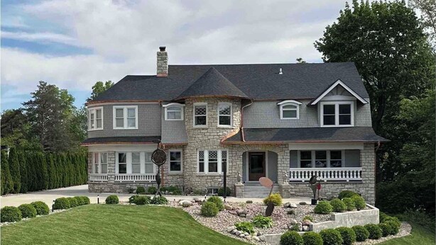 A large stone house with a wrap-around porch, multiple windows, and a well-maintained front yard. - Historic Oscar Lofquist House Heart of Des Moines (Des Moines)