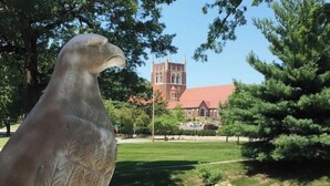 A large bird sculpture in a park with a church in the background. - Historic Oscar Lofquist House Heart of Des Moines (Des Moines)
