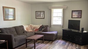 Een woonkamer met een modulaire bank, een salontafel, een tv-meubel en een plafondventilator.