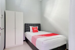 Ein Schlafzimmer mit einem Bett, einem Kleiderschrank und einem roten Kissen mit dem Schriftzug 'OYO'.