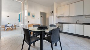 Una cocina moderna con armarios blancos, una mesa de comedor con sillas y un reloj visible en la pared.