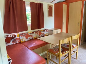 Una habitación pequeña con una zona de estar con banco, una mesa y una puerta.