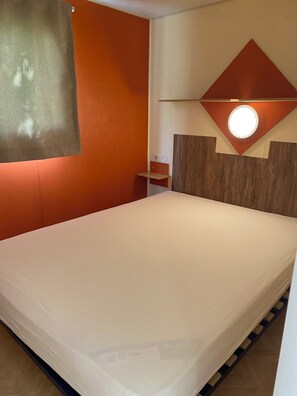 Une chambre d’hôtel avec un lit, une petite table de chevet, une lampe fixée au mur et un décor mural en panneaux de bois.