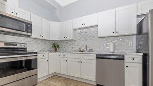 A modern kitchen with white cabinets, stainless steel appliances, and a tiled backsplash.