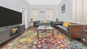 A living room with a sofa, coffee table, TV, and a patterned rug.