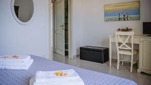 Une chambre d’hôtel avec deux lits, un bureau, une chaise, un tableau et une valise.