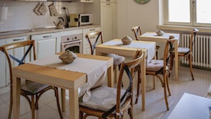 Un espace repas avec des tables et des chaises en bois, un four à micro-ondes et des placards, le tout dans un décor de cuisine.