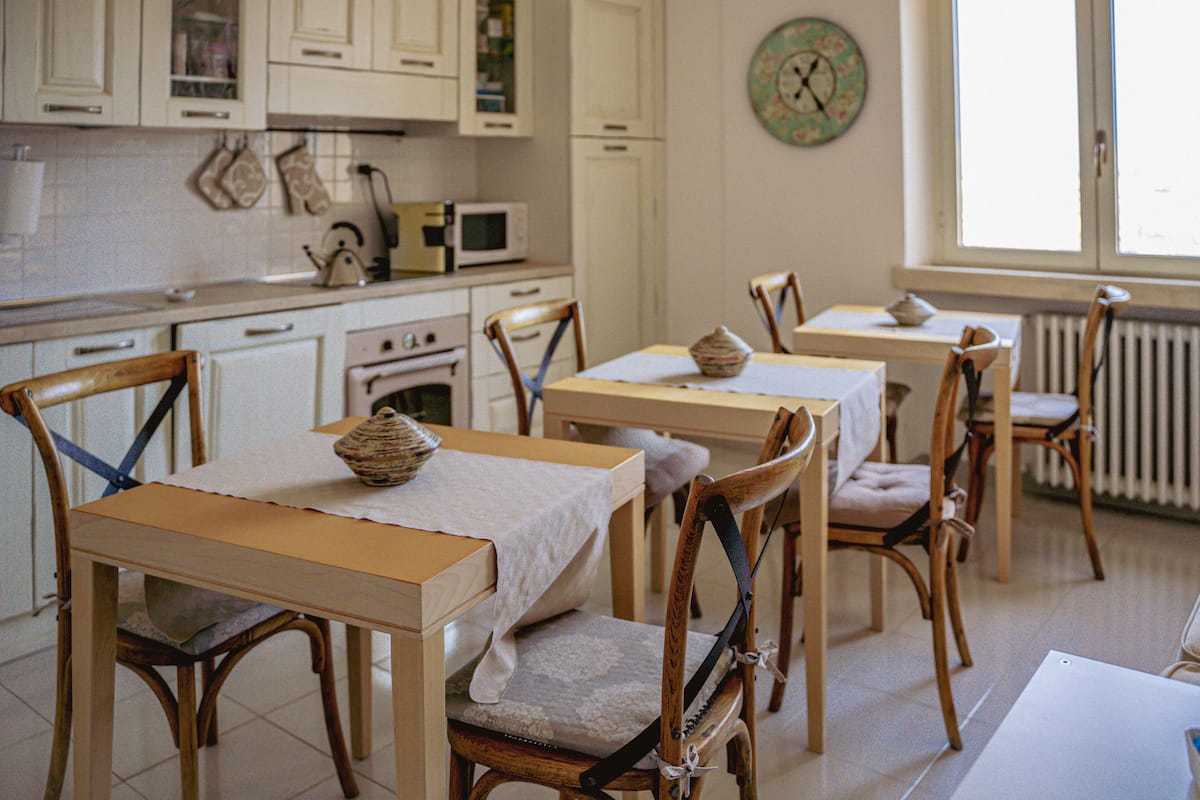 Un espace repas avec des tables et des chaises en bois, un four à micro-ondes et des placards, le tout dans un décor de cuisine.