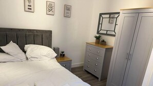A bedroom with a bed, bedside table, dresser, wardrobe, and wall art. - Flat in Luton Town Centre (Luton)