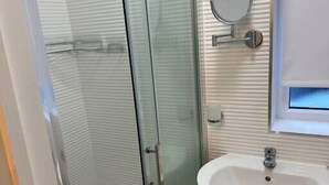 A bathroom with a glass shower enclosure, a white sink, and a mirror. - Flat in Luton Town Centre (Luton)