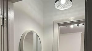 A hallway with a round mirror on the wall, a door leading to another room, and a ceiling light fixture. - Flat in Luton Town Centre (Luton)