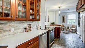 A kitchen with wooden cabinets, a dishwasher, and a stove. - Cozy Dark & Moody Home, New Reno, 10 mins to Lanc! (Mountville)