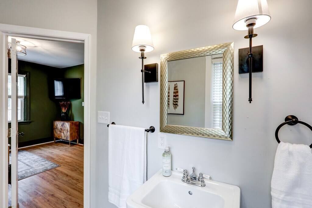 A bathroom with a white sink, a mirror with a decorative frame, and two wall-mounted lights.