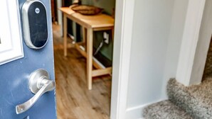 A blue door with a Yale lock and a keyhole, leading to a room with a wooden floor and a small table with a basket on it. - Cozy Dark & Moody Home, New Reno, 10 mins to Lanc! (Mountville)