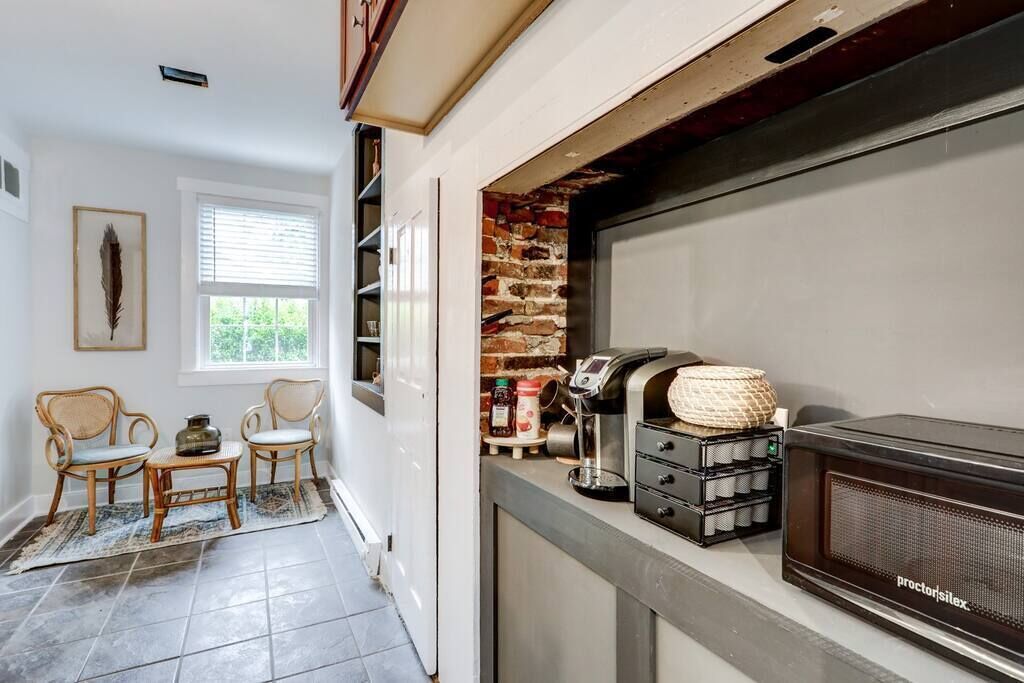 Una cocina con cafetera, microondas y cestas de mimbre en la encimera.