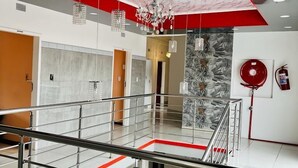 Un interior moderno con techo de mármol, pared de acento roja y barandilla de cristal con vistas a un nivel inferior.