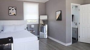 Un dormitorio con una cama, una mesita de noche, un espejo y una puerta que da al baño.