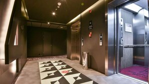 A modern hotel lobby with a geometric patterned carpet, a reception desk, and an elevator. - Ibis Baku City Hotel (Baku)