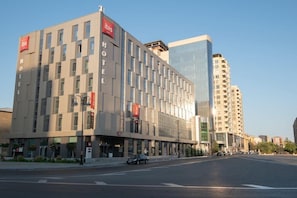 A modern hotel with a prominent 'Ibis' sign, a glass facade, and a corner location. - Ibis Baku City Hotel (Baku)