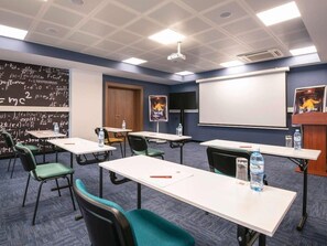 A conference room with white tables, teal chairs, a projector screen, a whiteboard with mathematical equations, and a water dispenser. - Ibis Baku City Hotel (Baku)