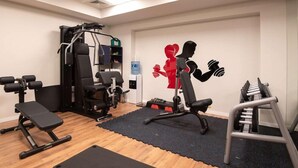 A gym with various exercise equipment, including a bench, weight bench, and a squat rack. - Ibis Baku City Hotel (Baku)