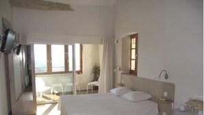 A bedroom with a large bed, a bedside table, a dresser, and a window with curtains. - Characteristic stone house (Le Poët-Laval)