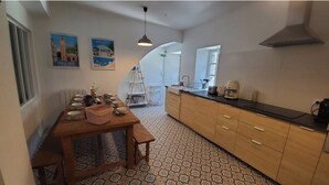 A kitchen with a wooden table set for dining, a sink, and a stove. - Characteristic stone house (Le Poët-Laval)