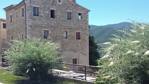 A stone building with multiple windows and a balcony. - Characteristic stone house (Le Poët-Laval)