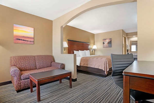 Quarto de hotel com sofá, cama, escrivaninha e cadeira.
