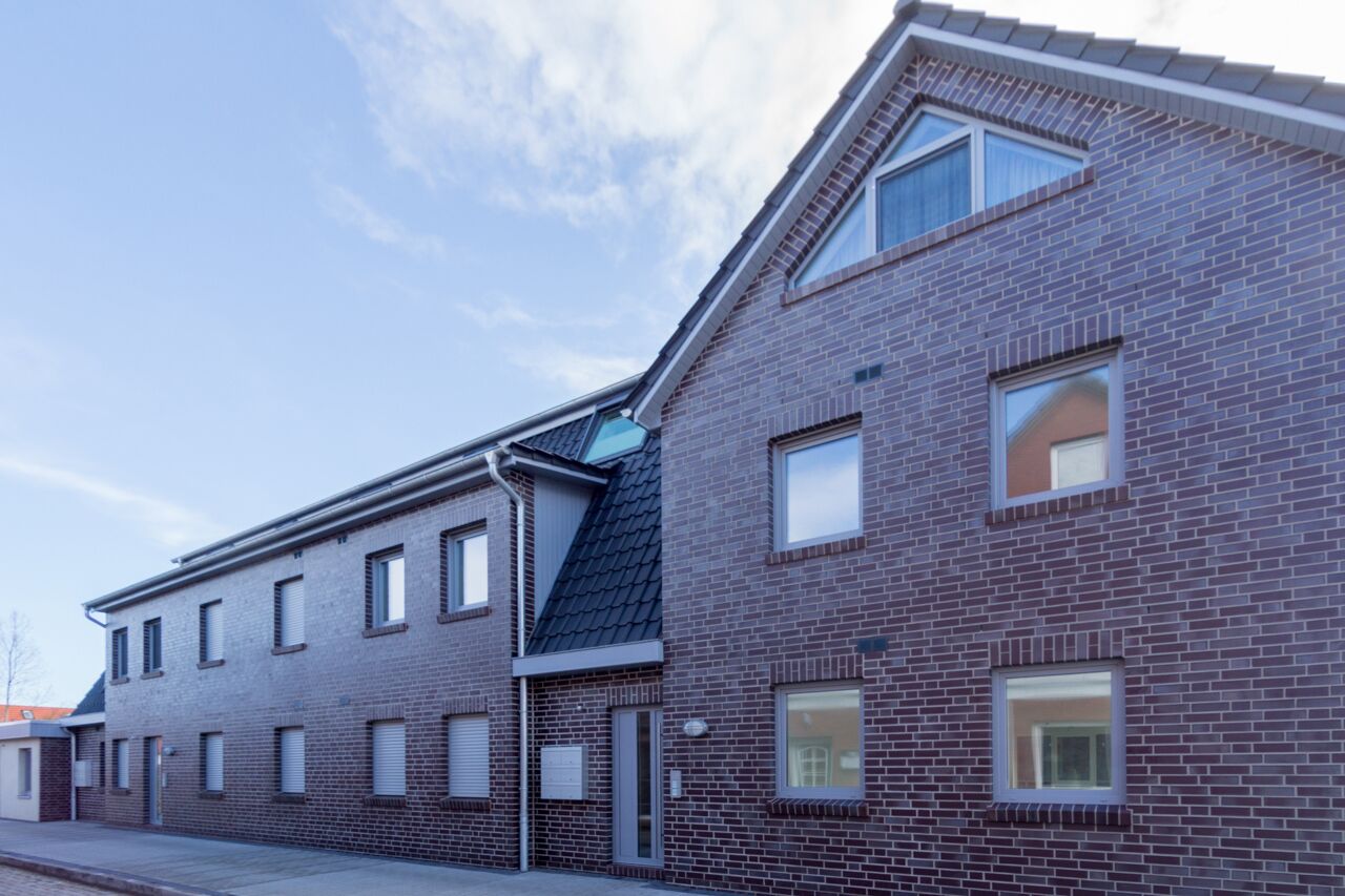 Un bâtiment moderne en briques, doté de nombreuses fenêtres et d’un toit en pente.