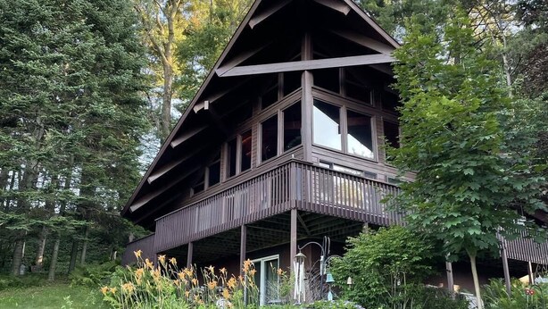 Eine Holzhütte mit Balkon, umgeben von dichtem Wald.