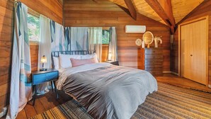 Een houten slaapkamer met een bed, nachtkastjes en een dressoir.
