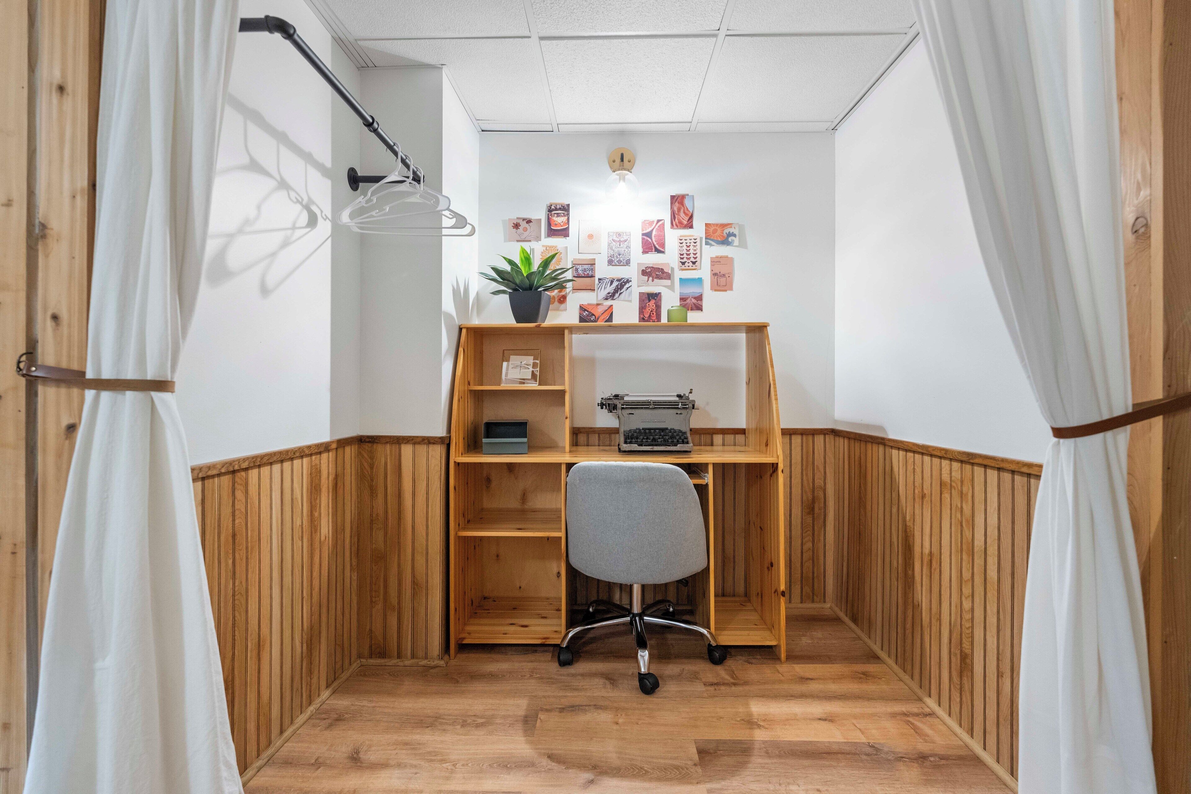 A corner office with a wooden desk, a typewriter, and a potted plant.
