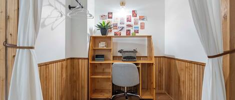 A corner office with a wooden desk, a typewriter, and a potted plant.