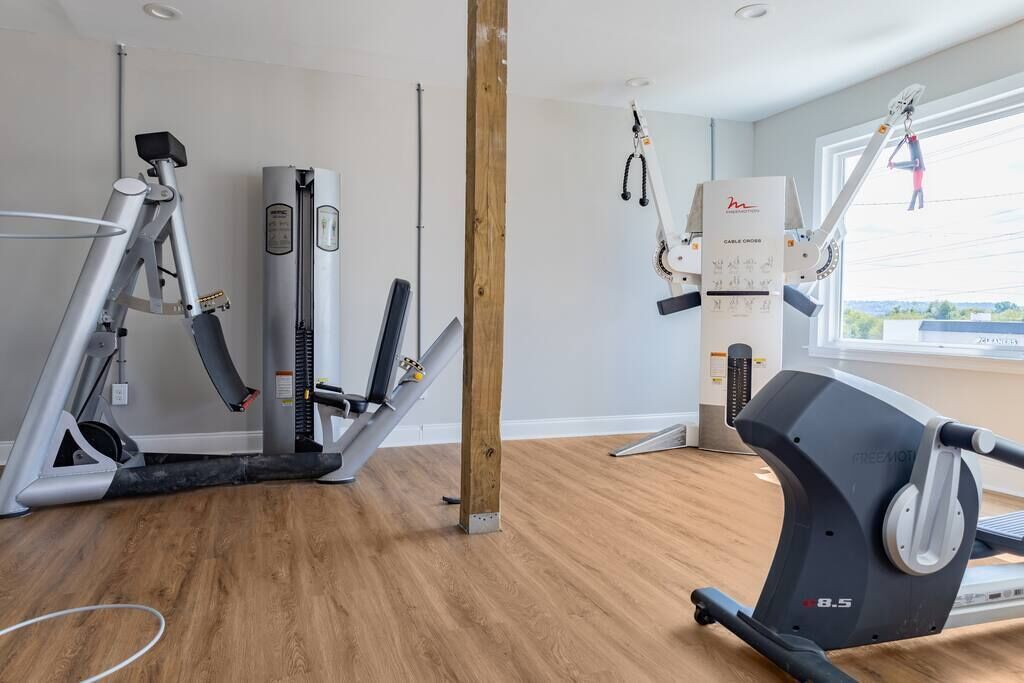 A gym with cardio machines, a cable cross trainer, and a pull-up bar.