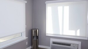 Ein Zimmer mit Fenster, Wandklimaanlage und Mülleimer.
