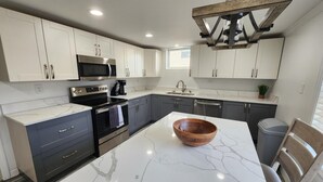 A modern kitchen with white marble countertops, stainless steel appliances, and grey cabinetry. - Lake Front, Family fun- Sleeps 8, Newly modern remodeled 3bed/2bath private dock (Creal Springs)