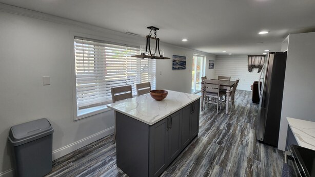 A modern kitchen with a marble island, wooden chairs, and a dining table. - Lake Front, Family fun- Sleeps 8, Newly modern remodeled 3bed/2bath private dock (Creal Springs)