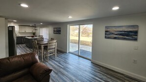 A modern kitchen with a dining area, a sliding glass door to the outdoors, and a brown leather couch. - Lake Front, Family fun- Sleeps 8, Newly modern remodeled 3bed/2bath private dock (Creal Springs)