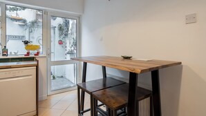 A kitchen with a wooden table, a dishwasher, and a view of the street outside.