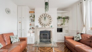 A living room with a fireplace, two leather sofas, a glass coffee table, and white cabinetry.