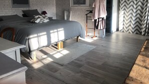Quarto moderno com cama, escrivaninha, cadeira, luminária pendente, quadro emoldurado e janela com cortinas.