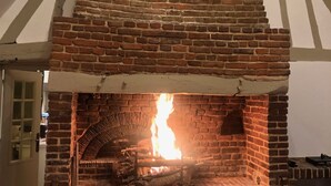Lareira de tijolos com fogo aceso, envolta por uma estrutura com moldura branca.