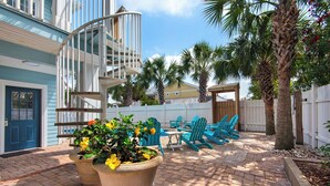 A patio with outdoor seating, a spiral staircase, and potted plants. - Tranquility 🌴 Huge Pool, Game Room, Sleeps 32, Pet-Friendly, Steps to Beach! (Pensacola Beach)