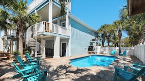 A pool area with a blue pool, outdoor seating, and a covered patio. - Tranquility 🌴 Huge Pool, Game Room, Sleeps 32, Pet-Friendly, Steps to Beach! (Pensacola Beach)