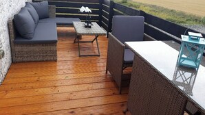A covered outdoor seating area with a sofa, chairs, a table, and a lantern.