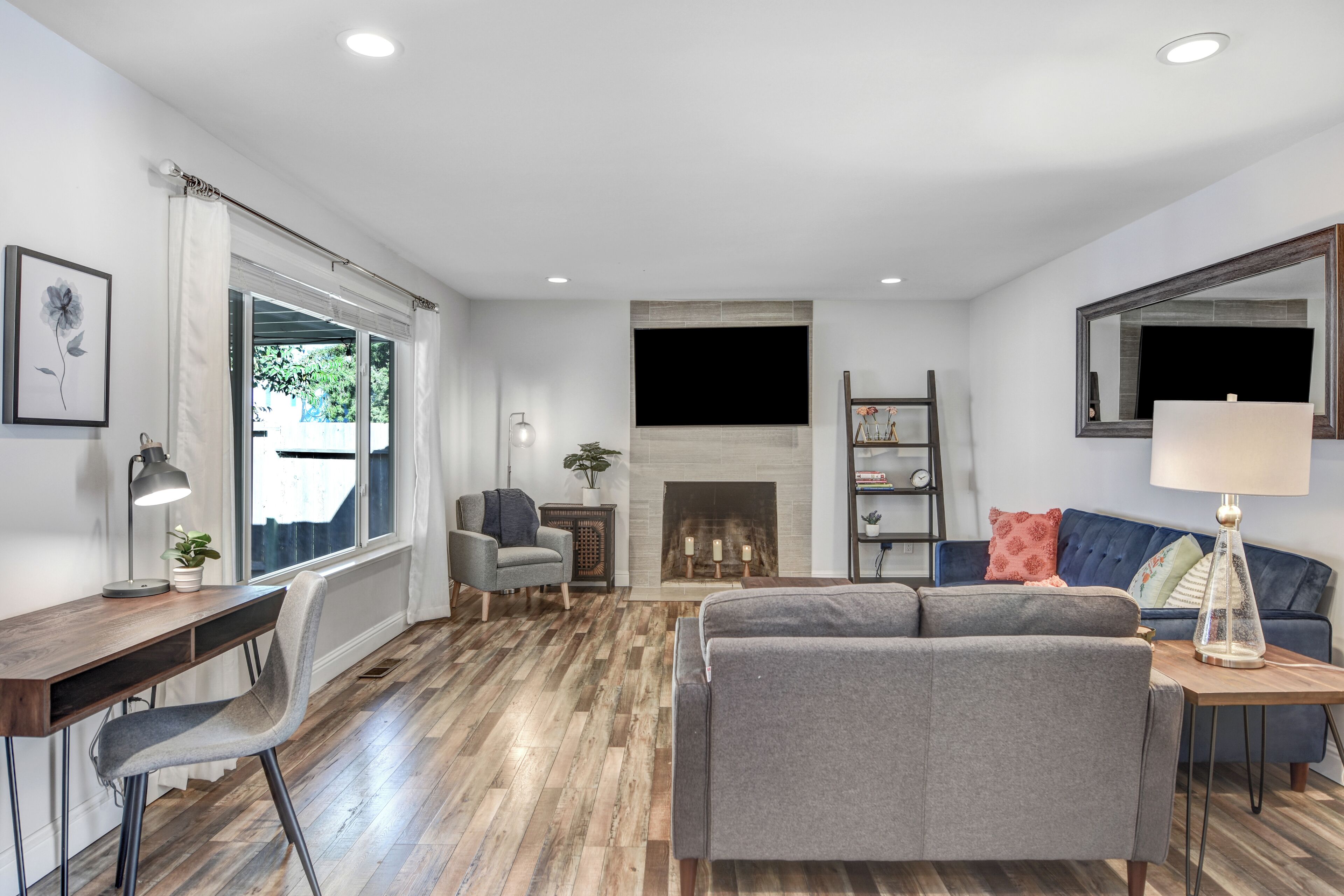 A living room with a fireplace, a sofa, a desk, and a chair.