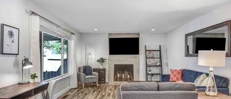 A living room with a fireplace, a sofa, a desk, and a chair.